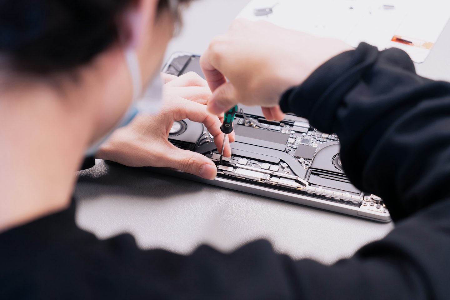 Technicien réparant des composants d'ordinateur portable sur un établi.