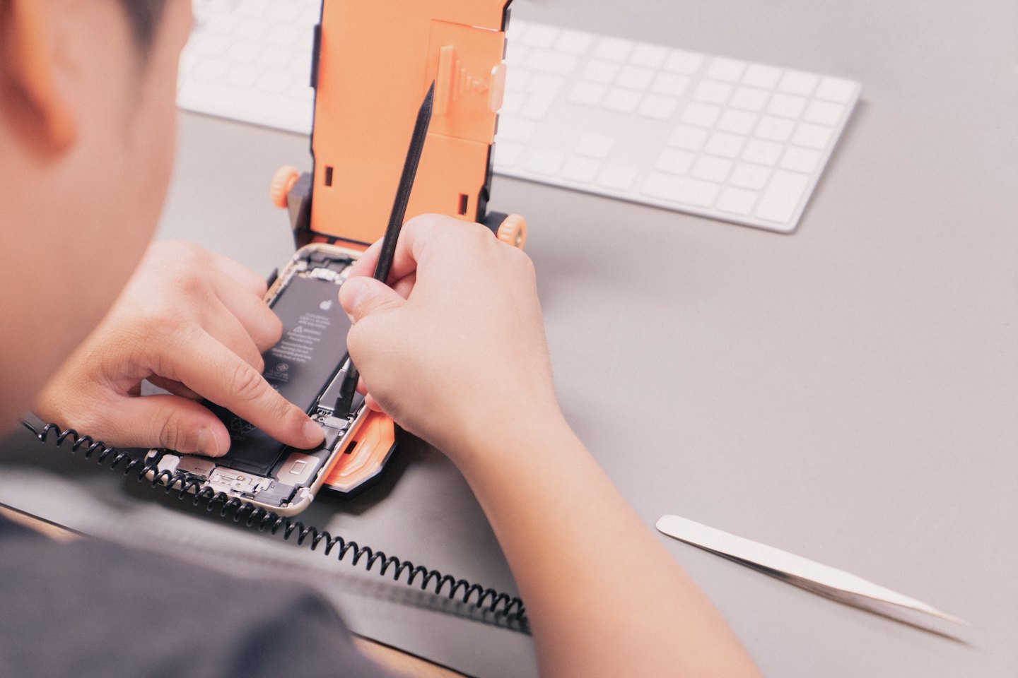 Mains d'un technicien réparant un smartphone ouvert avec des outils.