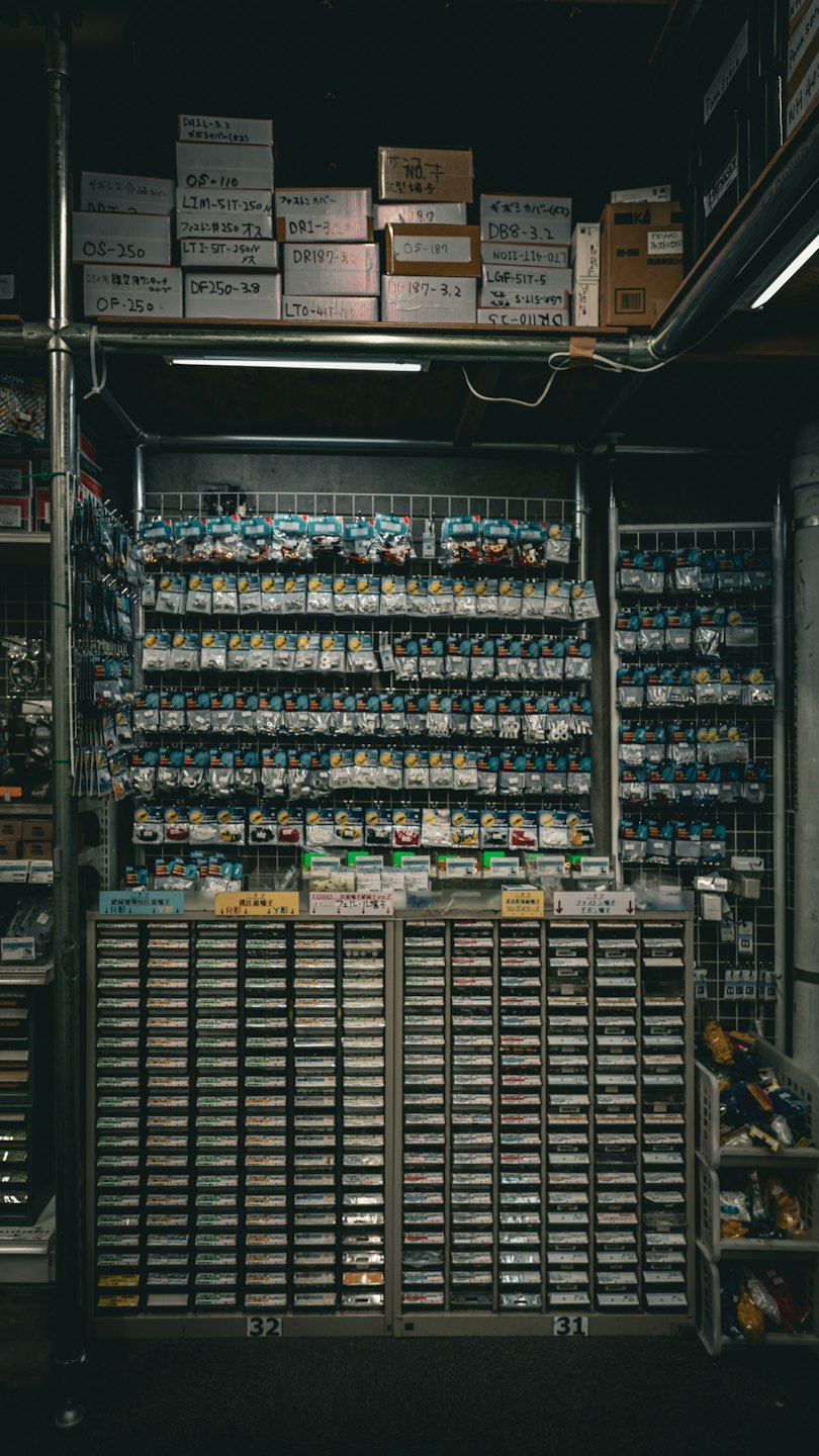 Petits composants électroniques organisés en sachets plastiques sur un mur perforé.